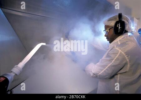 Austin Texas USA, 1994: High TECH Clean Room: Impiegato in 'Bunny Suit' mira a spruzzare CO2 cristalli pressurizzati sui componenti del computer all'interno di High-tec Foto Stock