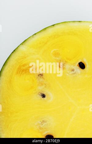 Mezza melone giallo succoso su fondo bianco, consistenza di pasta succosa e mesmes di anguria matura Foto Stock