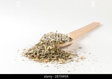 Erba di legno di Erba o in latino erba di Absinthii in cucchiaio di legno isolato su sfondo bianco. Erbe medicinali curative. Medicina erboristica. Farmaco alternativo Foto Stock