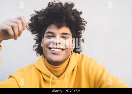Afro sorridente uomo ritratto - misto razza giovane ragazzo divertirsi posando nella fotocamera anteriore Foto Stock