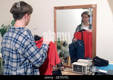 Austin Texas USA: Ragazzo di 13 anni guarda i vestiti nello specchio prima di scegliere cosa indossare. SIGNOR ©Bob Daemmrich Foto Stock