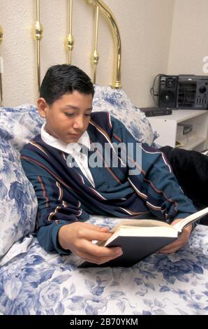 Austin, Texas Stati Uniti d'America: Ispanico 13 anni ragazzo lettura per divertimento a casa. SIGNOR ©Bob Daemmrich Foto Stock