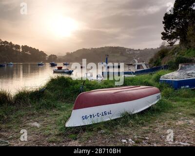 Piccole barche da pesca e vista sul fiume Brazo Mayor e la palude di Pombo a San Vicente de la Barquera, Cantabria, Spagna Foto Stock