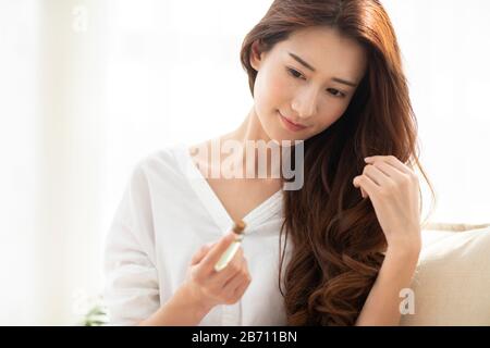 Giovane donna cinese che applica l'olio essenziale sui capelli Foto Stock
