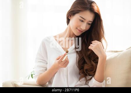 Giovane donna cinese che applica l'olio essenziale sui capelli Foto Stock
