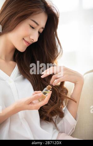 Giovane donna cinese che applica l'olio essenziale sui capelli Foto Stock