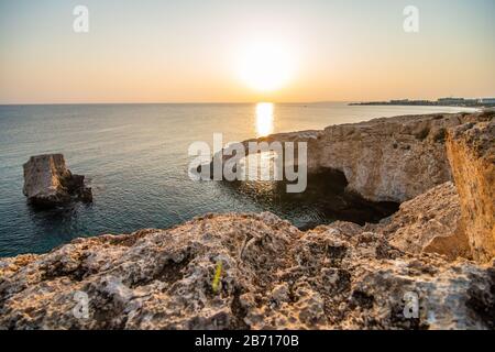 Bellissimo tramonto sul ponte di pietra naturale vicino Ayia Napa su Cipro. Ponte d'amore. Cavo greco Foto Stock