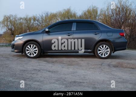 Oleksandrivka, regione di Dnipropetrovsk, Ucraina - 10 marzo 2020: Toyota Corolla colore grigio sulla riva del fiume Samara al crepuscolo Foto Stock