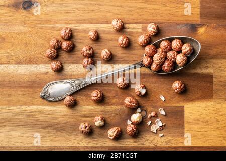 Nocciole con glassa di zucchero nel cucchiaio su tavola di legno. Vista dall'alto. Foto Stock