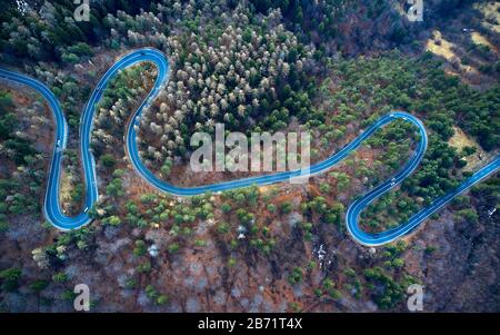 La vista aerea di strada tortuosa da alto passo di montagna con gli alberi in Transilvania, Romania, vista su strada curva da drone in autunno-inverno Foto Stock