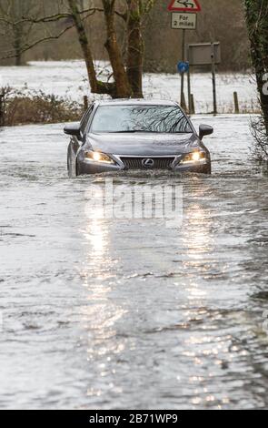 Inondazioni causate da Storm Ciara al ponte Rothay di Ambleside, Lake District, Regno Unito, con auto che attraversano le inondazioni. Foto Stock