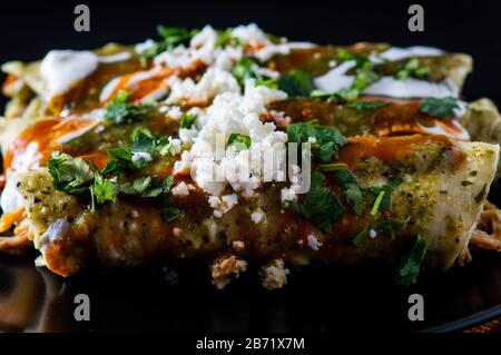 Enchiladas Verdes, o enchiladas verde, tortillas ripieno di pollo e condito con salsa verde, formaggio e crema Foto Stock