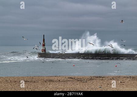 Onde giganti che si infrangono sul frangiflutti e il faro su Aguda Beach, Miramar, Arcozelos città Foto Stock