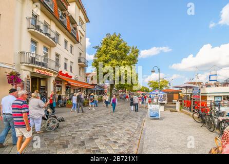 I turisti possono godersi una giornata di sole sul lungomare lungo il canale Alter Strom a Warnemunde Rostock, in Germania. Foto Stock