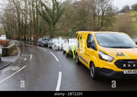 Alluvione causata da Storm Ciara al Rothay Bridge di Ambleside, Lake District, Regno Unito, con un furgone AA che raccoglie auto che si sono abbattute nell'alluvione Foto Stock