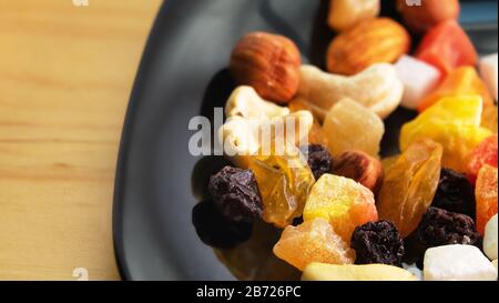 Tutti frutti. Mix di frutta secca (uva passa, cedro, mango) e dadi (mandorle, nocciole) su un nero laccato piatto Foto Stock