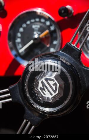 Centro del volante con razze metalliche e cruscotto rosso in Classic British MG MGA sportscar esposto al rally automobilistico di Oxfordshire, Regno Unito Foto Stock