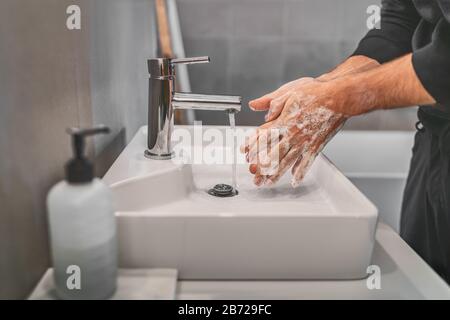 Lavando le mani con sapone e acqua calda a casa lavabo bagno uomo pulizia igiene delle mani per la prevenzione di focolai di coronavirus. Corona Virus protezione pandemica lavando frequentemente le mani. Foto Stock