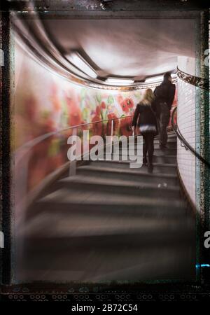 Persone che scalano le scale con un colorato murale di fiori su un lato nella stazione della metropolitana Abbesses, Montmartre, Right Bank, Parigi, Francia, Europa, colore Foto Stock