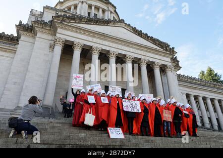 OLYMPIA, WA, 14 OTTOBRE 2017: Uomini e donne vestiti con i costumi della Handmaid's tale si radunano sui gradini del campidoglio dello stato di Washington per protestare contro Trump Foto Stock