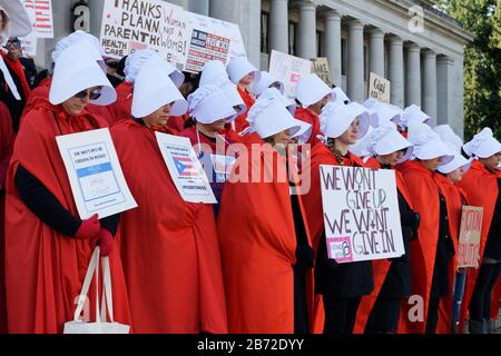 OLYMPIA, WA, 14 OTTOBRE 2017: Uomini e donne vestiti con i costumi della Handmaid's tale si radunano sui gradini del campidoglio dello stato di Washington per protestare contro Trump Foto Stock