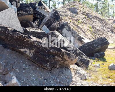 Montagna di strada demolizioni pavimentazione, asfalto e calcestruzzo macerie, sabbia, ghiaia, aggregati in primo piano, enorme pile di sabbia sfondo, pini Foto Stock