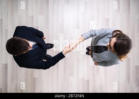 Direttamente Sopra Shot Di Uomini D'Affari Che Scuotono Le Mani Mentre Si Sta In Piedi Su Pavimento Piastrellato In Ufficio Foto Stock