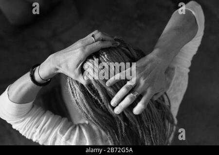 Le mani belle tessono i Dreadlock in una treccia. Vista dall'alto Foto Stock