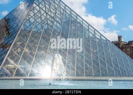Francia. Giornata di sole a Parigi. Piramide di vetro e fontana nel cortile del Museo del Louvre da vicino Foto Stock