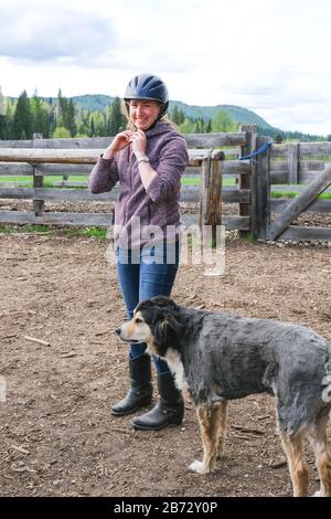 Una giovane donna con un cane che si prepara ad andare a cavallo nel parco nazionale di Banff. Foto Stock