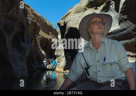 La guida turistica femminile di Cobbold Gorge, guiderà la sua barca lungo le strette pareti della gola mentre un'altra guida turistica si avvicina da dietro. Foto Stock