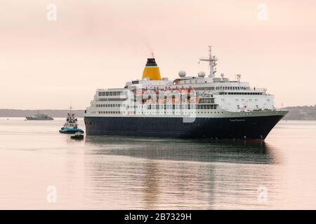 Cobh, Cork, Irlanda. 13 Marzo 2020 . Lavorare in barca Geata Bán e tirare Gerry o’Sullivan a portata di mano per assistere la nave da crociera Saga Sapphire mentre si fa strada fino al porto prima dell'alba. Con 752 passeggeri a bordo, era originariamente destinata ad ormeggiare a Cobh, ma con nuove misure in atto per combattere la diffusione di Covid-19 il suo ormeggio fu cambiato in Ringaskiddy, Co. Cork, Irlanda. - Credito; David Creedon / Alamy Live News Foto Stock