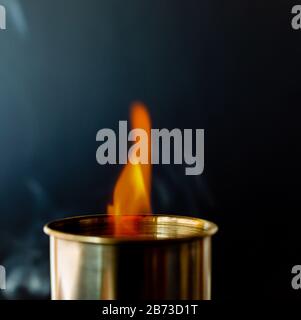 Fiamma, candela bruciante su sfondo nero. Candela di ottone. Pericolo. Fuoco e fumo. Foto Stock