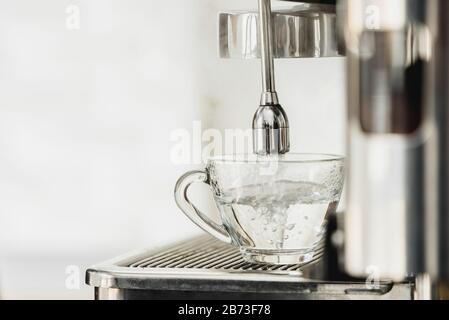 Acqua calda dalla macchina per il caffè che scorre nella tazza per la preparazione di Americano Foto Stock