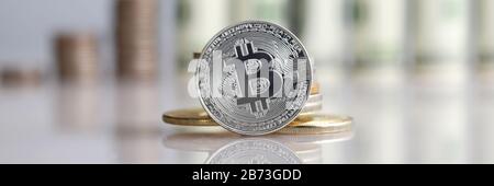 Sul tavolo si trova moneta bitcoin su fondo dollari Foto Stock