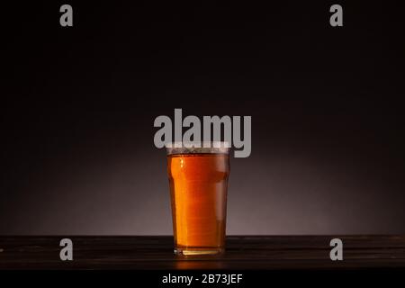 Pinta di birra ancora vita messa a punto con tavolo scuro e illuminazione minima. Sfondo scuro con spazio di copia e spazio di testo. Foto Stock