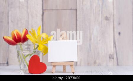 Tulipano fiore in vaso di vetro con cornice decorazione su tavolo in legno muro di fondo a casa, primo piano, concetto di design Festa della mamma. Foto Stock