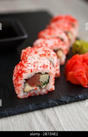 Sushi roll con frutti di mare e salsa di soia, wasabi e zenzero. Sushi rotola su una lavagna nera.