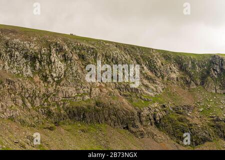 Una locomotiva con una sola carrozza passa per una ripida scogliera sulla Snowdon Mountain Railway, Snowdonia National Park, Galles, Regno Unito. Foto Stock