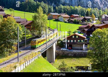 Lauterbrunnen, Svizzera - 10 ottobre 2019: Case di legno alpine e treno Wengernalpbahn, Alpi svizzere, regione della Jungfrau Foto Stock