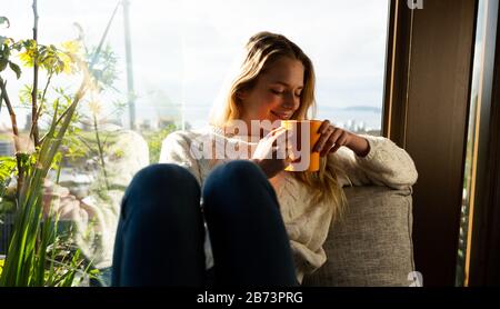 Donna che beve caffè in poltrona Foto Stock