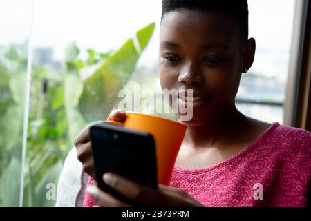 Donna che usa il telefono e beve caffè Foto Stock