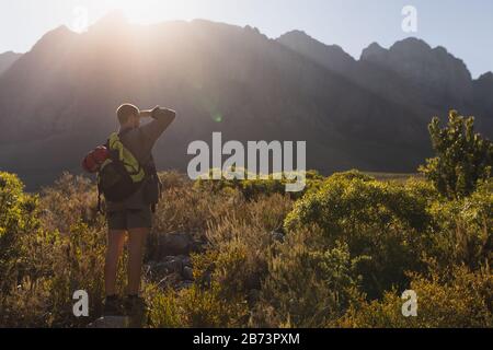 Vista posteriore dell'uomo su una roccia che guarda lontano Foto Stock