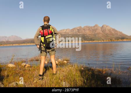 Vista posteriore dell'uomo con zaino davanti a un lago Foto Stock