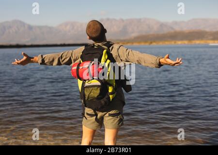 Vista posteriore dell'uomo con zaino davanti a un lago Foto Stock