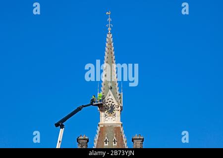 Fettes College Building, Edimburgo, Scozia, Regno Unito. 13th Mar 2020. Addetti alla manutenzione sulla piattaforma di un'enorme gru, verifiche effettuate sulla torre dell'orologio dell'edificio storico da parte di lavoratori in cappelli rigidi e giacche gialle. Questa scuola pubblica era notoriamente dove Tony Blair era istruito. Il Collegio è stato fondato nel 1870. Fu progettato da David Bryce, e completato (1864-70) in stile baronale scozzese. Foto Stock