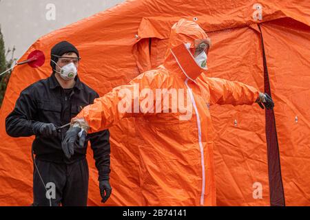 Kudowa Zdroj, Polonia. 13 Marzo 2020. Gli agenti di polizia di frontiera polacchi in tute protettive effettuano controlli medici e misurazioni della temperatura di conducenti e passeggeri provenienti dall'estero al valico di frontiera tra Polonia e Repubblica Ceca, il 13 marzo 2020, Nachod-Kudowa Zdroj, a causa delle preoccupazioni circa la diffusione del nuovo coronavirus. Sul poliziotto foto disinfetta il collega in tuta protettiva dopo uno dei controlli medici. Credit: David Tanecek/Ctk Photo/Alamy Live News Foto Stock