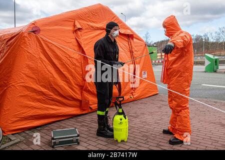 Kudowa Zdroj, Polonia. 13 Marzo 2020. Gli agenti di polizia di frontiera polacchi in tute protettive effettuano controlli medici e misurazioni della temperatura di conducenti e passeggeri provenienti dall'estero al valico di frontiera tra Polonia e Repubblica Ceca, il 13 marzo 2020, Nachod-Kudowa Zdroj, a causa delle preoccupazioni circa la diffusione del nuovo coronavirus. Sul poliziotto foto disinfetta il collega in tuta protettiva dopo uno dei controlli medici. Credit: David Tanecek/Ctk Photo/Alamy Live News Foto Stock