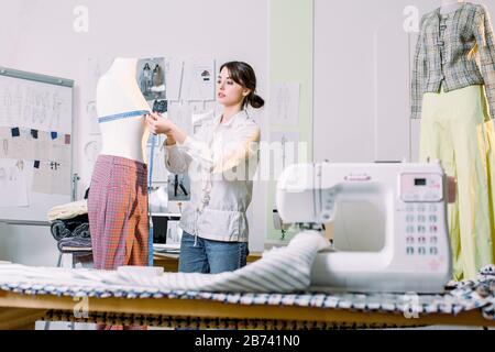 C'era un bell'apprettatore giovane in sala da lavoro. Design di moda concetto di misurazione Mannequini Foto Stock