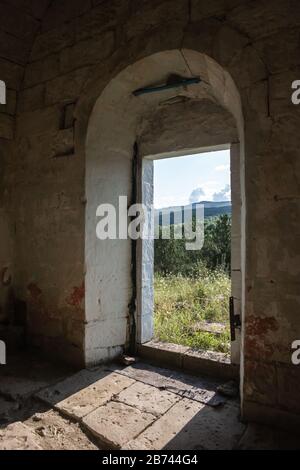 Abbandonato frammento interno della Chiesa, muro di pietra bianca con porta vuota Foto Stock